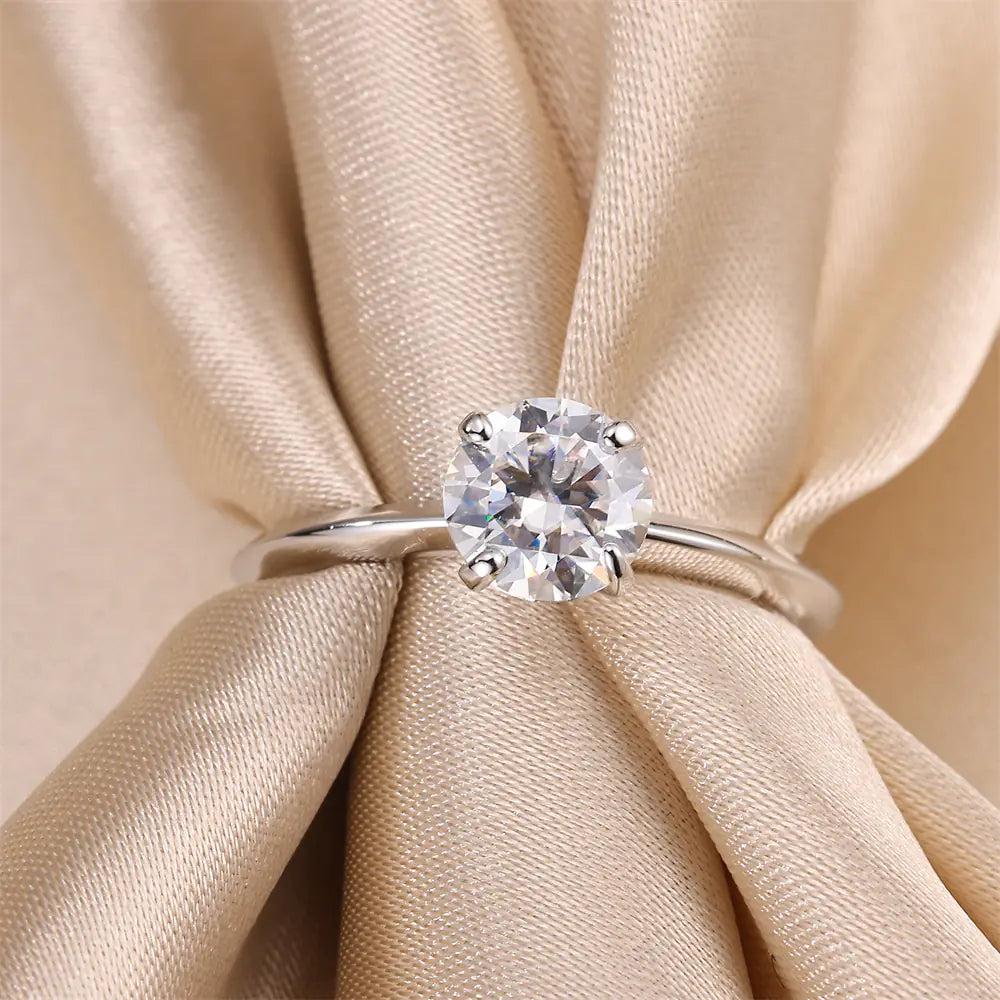 1 carat round moissanite solitaire ring resting on silk fabric